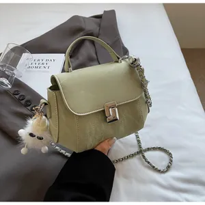Détail du sac matelassé vert clair avec boucles argentées et breloque monstre en peluche