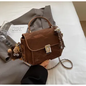Détail du sac marron en similicuir matelassé avec bandoulière chaîne et porte-clés