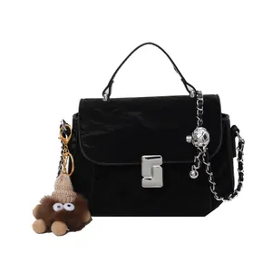 Sac bandoulière matelassé noir avec détails argentés et un petit pendentif monstre brun