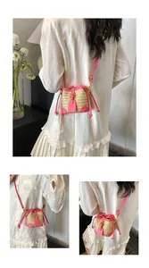 Gros plan d'un mini sac seau en paille avec bordure en cuir rose et cordon de serrage