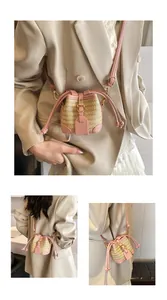 Détails des finitions en cuir rose et dorures sur un mini sac seau en paille