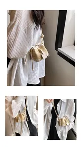 Vue détaillée du mini sac seau en paille avec bordure en cuir et finitions dorées