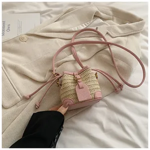 Détail des coutures en cuir PU rose et du tressage en paille d'un mini sac seau