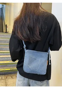 Detail of light blue denim crossbody bucket bag with retro pocket design and knot strap