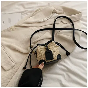 Détail d'un mini sac seau en paille avec garniture en cuir noir et cordon de serrage