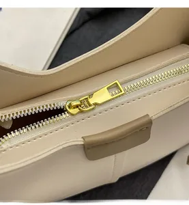 Gros plan d'une fermeture éclair dorée sur un sac cabas en simili cuir crème