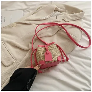 Détail d'un mini sac seau en paille rose avec fermeture à cordon et bandoulière en cuir