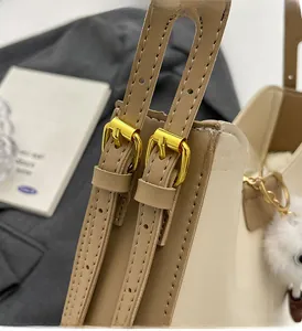 Détails des boucles dorées et de la bandoulière en cuir crème avec pompon décoratif