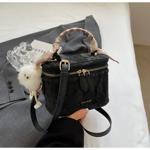 Detail of black textured bucket bag with silk scarf handle and plush pom charm