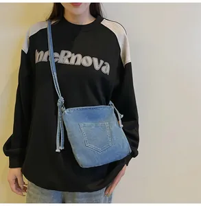 Detailed close-up of blue denim bucket bag featuring contrast stitching and a knotted strap