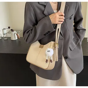 Détail du sac à bandoulière beige contrasté avec texture cuir et breloque peluche