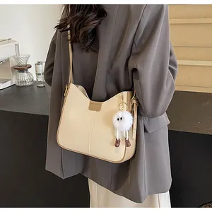 Détail du sac à bandoulière beige en similicuir avec charm peluche et sangle