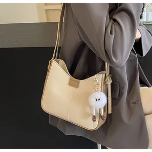 Détail du sac cabas crème avec fermoir en cuir marron et breloque peluche rigolote