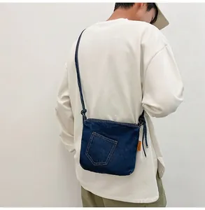 Detail of blue denim crossbody bucket bag showing side brand label and fabric texture