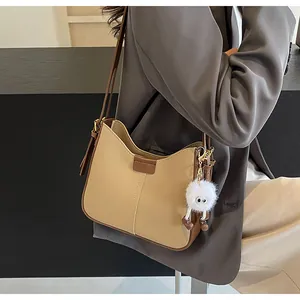 Détail du sac bandoulière bicolore avec ferrures dorées et breloque peluche blanche