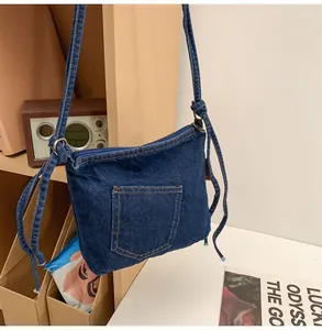Detailed view of deep blue denim bucket bag with front pocket and knotted shoulder strap