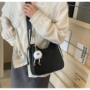 Détail du sac à bandoulière en similicuir noir avec un joli porte-clé monstre en peluche
