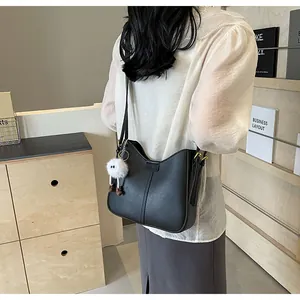 Détail du sac à bandoulière noir avec ouverture en V et pendentif en peluche
