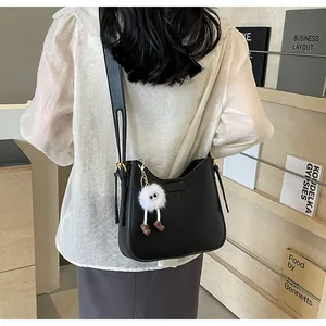 Détail du sac à bandoulière noir minimaliste avec un pendentif en peluche monstre