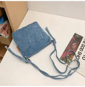 Close-up of denim crossbody bucket bag with pocket detail and adjustable knotted strap