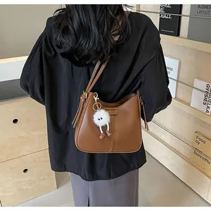 Sac fourre-tout en similicuir marron avec une peluche blanche dans un décor chaleureux