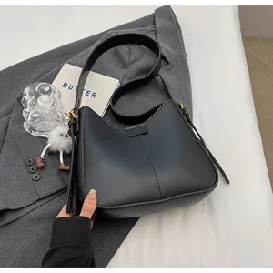 Vue détaillée du sac à bandoulière noir avec coutures et charm en peluche blanche