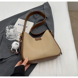 Détail du sac cabas en cuir kaki et marron avec un charm de monstre en peluche blanc