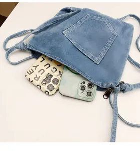 Detail view of denim crossbody bucket bag showing interior space for two smartphones