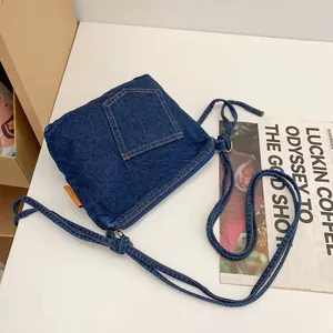 Blue denim bucket bag with vintage patchwork and front pocket detail on white desk