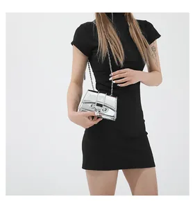 Détail d'un sac à chaîne argenté métallisé brillant avec boucle en U porté par un mannequin