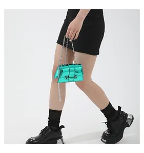 Détail du mini sac à chaîne vert métallique montrant le cuir verni brillant et la boucle argentée