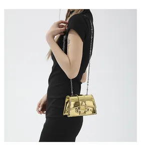 Détail d'un mini sac doré brillant avec finition métallique et bandoulière en chaîne