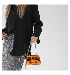 Détail du mini sac orange en cuir verni brillant avec bandoulière chaîne argentée