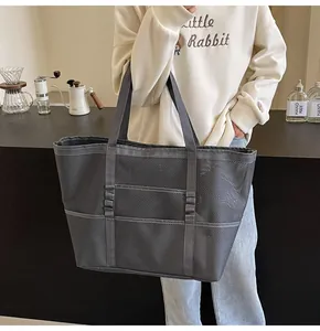 Detalle del bolso tote de malla gris con asas anchas en un ambiente de café moderno