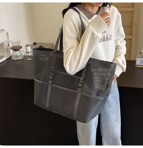 Detalle del bolso tote de malla gris oscuro con bolsillos frontales y asas resistentes