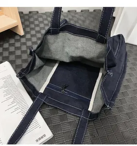 Close-up of unlined dark blue denim tote bag with contrast stitching and metal zip pocket