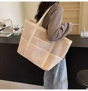 Detalle de la textura de malla transpirable y el asa de cincha reforzada en el bolso beige
