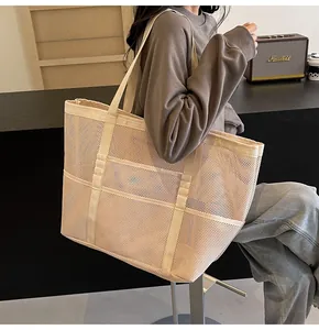 Detalle de bolso tote de malla crema con múltiples bolsillos y correas reforzadas