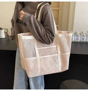 Primer plano de un bolso tote de malla grande con correas reforzadas y varios bolsillos