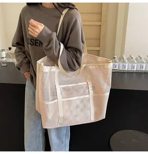 Detalle de un gran bolso tote de malla rosa con bolsillo lateral y asa de lona