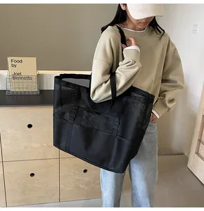 Detalle de un bolso tote de malla negra con bolsillos exteriores llevado por una modelo