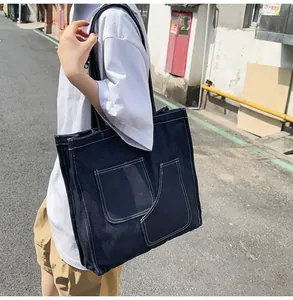 Detail of dark blue denim tote bag with white contrast stitching and large front pockets