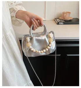 Detail of silver cloud bag with pleated metallic finish and marble bead chain accessory