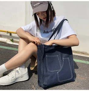 Detail of spacious dark blue denim tote bag with contrast stitching and dual front pockets
