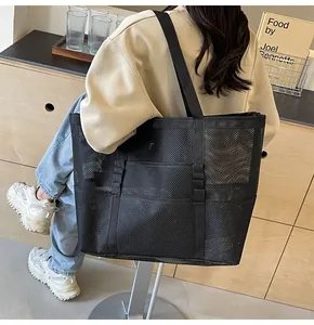 Foto de estilo de vida de un bolso tote de malla negra con correas y varios bolsillos