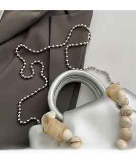 Detail of silver handbag with marble-style resin chain and circular metal handle