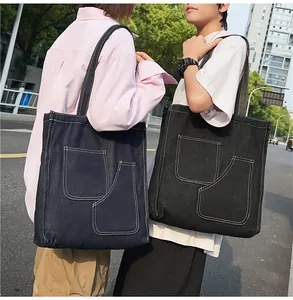 Detail of large denim tote bags with contrast stitching and functional outer pockets
