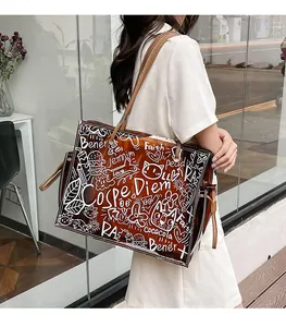 Detail of transparent brown jelly tote bag featuring white graffiti art and leather handles
