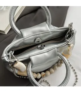 Detailed macro view of silver metallic leather handbag with magnetic closure and beaded chain