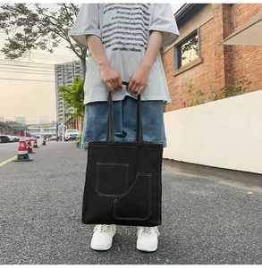 Detail view of black canvas tote bag with contrast stitching and dual functional pockets